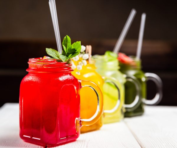 4 different refreshing summer lemonades in jars, red, orange, yellow and green