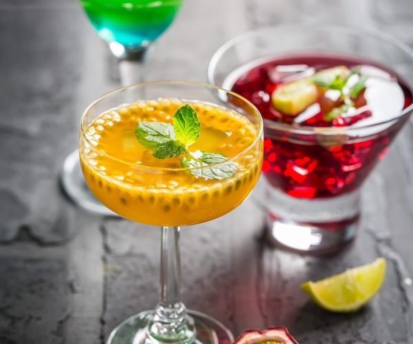 Assortment of different cocktails with fresh fruits, ice and mint on black background.