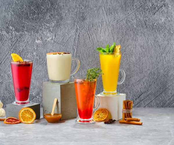 Composition with hot fruit and herbal winter drinks on shabby grey background