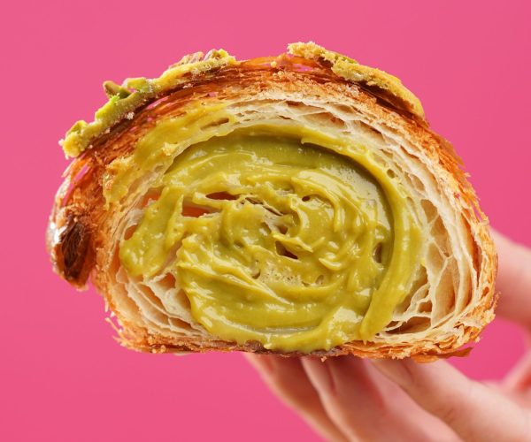Freshly baked croissant held in hand on colorful background