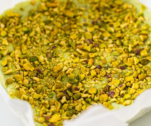 Scoring pistachio fudge using a wheel dough cutter for cutting into small square pieces.