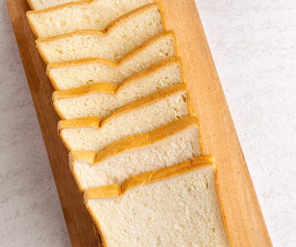 Stack of sliced white bread on cutting board. White background texture. Flat lay.