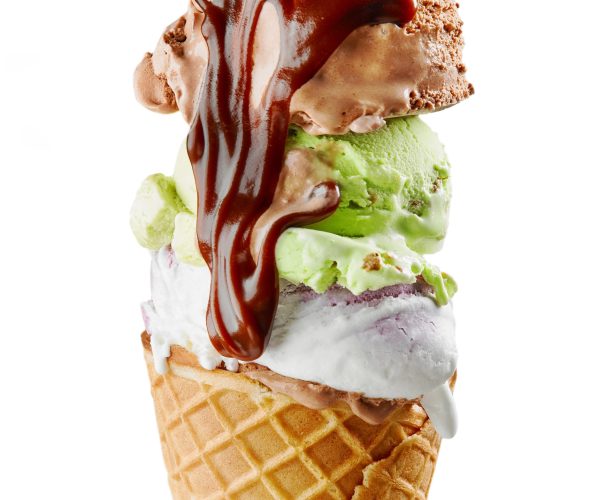 various ice cream balls with chocolate sauce in waffle cone isolated on white background